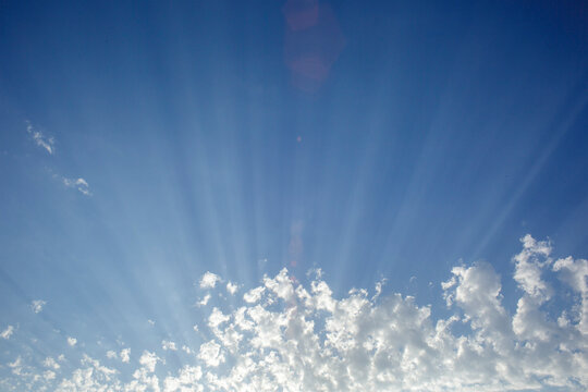 Blue Sky With Clouds And Sun Rays Coming Out Of The Clouds