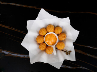 The cheese balls in the dish with black background