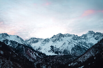 Obraz premium beautiful snow-capped big mountains at dawn with scarlet color clouds