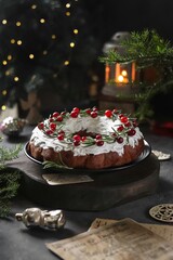 Christmas cupcake with dried fruits, nuts, white icing, decorated with rosemary and cranberries on a dark background with bokeh