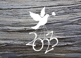 A dove carries the numbers of the new year 2023 on a wooden background