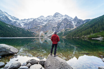 Naklejka premium Morskie Oko or Sea Eye Lake, famous tourist destination in Tatra National Park, near Zakopane, Poland. Five Lakes Valley in mountains. Beautiful Polish landscape. Man standing on a rock.