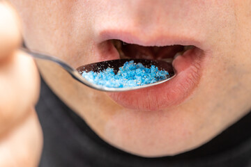 Microplastic in food, Environment and health concept, Person putting a spoon with plastic particles in his mouth - obrazy, fototapety, plakaty