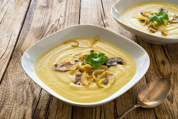 Cauliflower creamy soup with fried onion and mushrooms on wooden table
