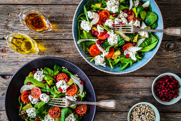Fresh vegetable salad with feta cheese and pomegranate on wooden table
