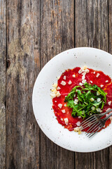 Beef carpaccio with parmesan and arugula on wooden table
