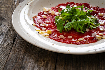 Beef carpaccio with parmesan and arugula on wooden table
