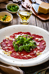 Beef carpaccio with parmesan and arugula on wooden table
