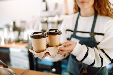 Сoffee to go. Young barista girl smiling happy holding take away coffee at the cafe shop.
