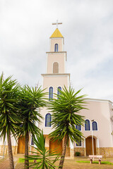 Fototapeta na wymiar Vista frontal da Paróquia Nossa Senhora D'abadia, entre plantas, na cidade de Anápolis em Goiás em um dia nublado.