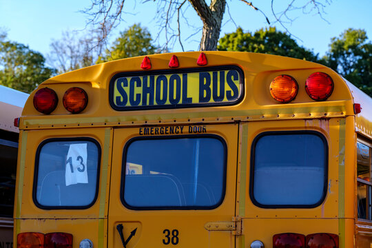 Top of a yellow school bus with lights and text. Closeup against blue sky in the fall. Back to school concept. Copy space. High quality photo