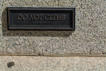 Do not climb, the metal sign on a granite wall. High-quality photo