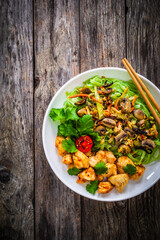 Asian food - green tea noodles, stir fried vegetables, soy sauce and mushrooms on wooden table
