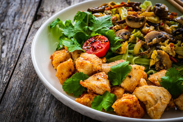 Asian food - green tea noodles, stir fried vegetables, soy sauce and mushrooms on wooden table
