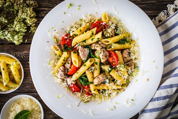 Roasted chicken nuggets, cherry tomatoes, spinach and penne served on wooden table
