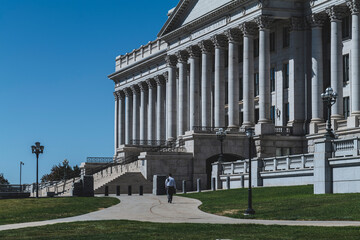 Fototapeta na wymiar A lone man walks away in front of the Capitol building on a sunny day. High-quality photo