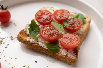 toasts with feta cheese and cherry tomatoes on a white dish, macro shot, healthy snack