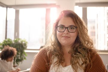 Portrait of a girl in foreground, looking at the camera in the office