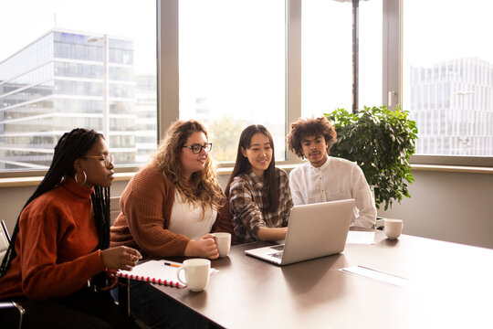 Group of four young people , working in the office in front of a computer