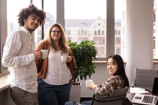 Small group of young friends taking coffee in the office