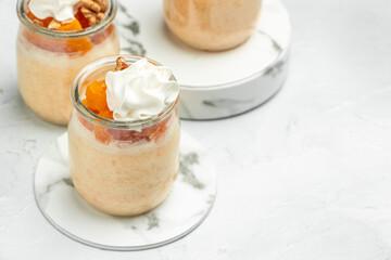 dessert with pumpkin, whipped cream. Pumpkin parfait with nuts in glass on a light background. banner, menu, recipe place for text, top view