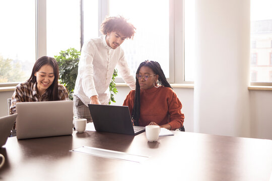 Concentrated group of young people work in a office, with laptop