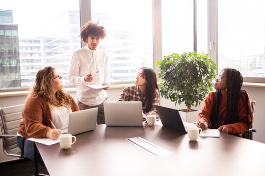 Concentrated group of young people work in a office, with laptop