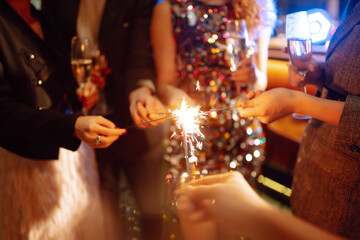 Sparkling sparklers in the hands of friends.Group of people holding sparklers at party. Winter holidays, vacation, relax and lifestyle concept.