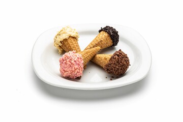 Isolated shot of a plate of different ice cream-shaped pastries on a cone on a white background