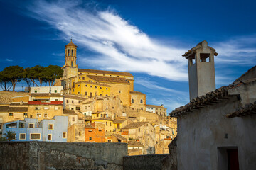 Obraz premium View of the colorful and historic old town of Cehegín with the Magdalena church in the background on a hill and a traditional house with a chimney in the foreground