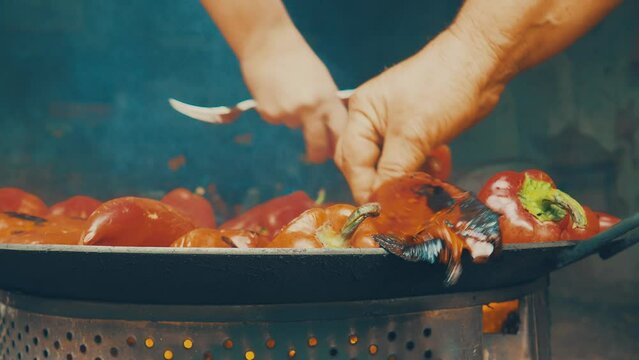 Roasting red peppers for a smoky flavor and quick peeling. Thermal processing of the pepper crop on a metal circle. Brazier container used to burn charcoal fuel for cooking, heating or cultural ritual