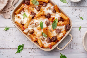 Pasta baked with meatballs and cheese in a skillet on a light slate, stone or concrete...