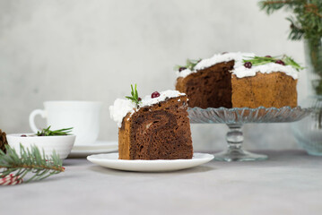 A piece of Christmas cake on plate on grey table with cup of tea and christmas cake on the glass stand.