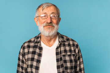 close-up portrait of a senior man thinking about something on blue background