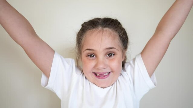 Portrait Child Girl Looking At The Camera. Happy Family Indoors Kid Dream Concept. Baby Eyes Down Then Look At The Camera And Smiles. Funny Portrait Girl Kid Close-up. Smile Teeth Fell Out