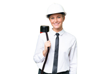 Young architect caucasian woman with helmet and holding blueprints over isolated background keeping...