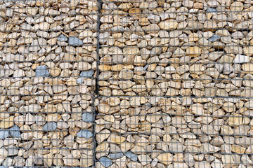 Stones placed behind a metal lattice to protect the side of a mountain