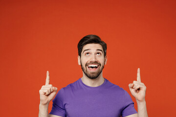 Young man wear casual basic purple t-shirt pointing index finger overhead on indicate on workspace...