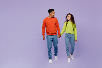 Fototapeta premium Full body young couple two friends family man woman of African American ethnicity wear casual clothes hold hands walk go together look to each other isolated on pastel plain light purple background.