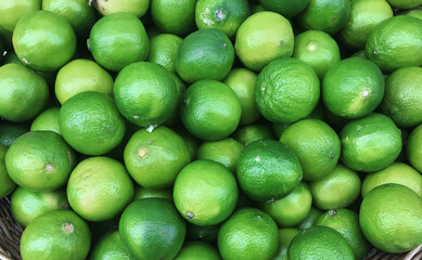 A straw basket with fresh limes as a background.