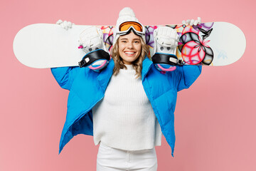 Snowboarder smiling woman wear blue suit goggles mask hat ski padded jacket hold snowboard behind neck isolated on plain pastel pink background. Winter extreme sport hobby weekend trip relax concept.