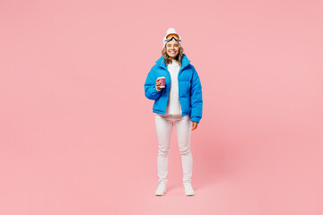 Snowboarder happy woman wear blue suit goggles mask hat ski padded jacket hold takeaway paper cup coffee to go isolated on plain pink background. Winter extreme sport hobby weekend trip relax concept. © ViDi Studio