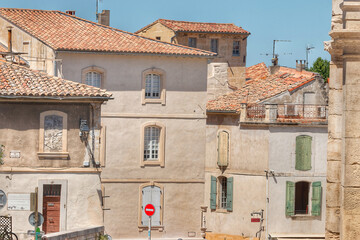 House roofs, building facades in a typical provence town, Arles, France. Houses with orange tiled roofs. Green shutters.