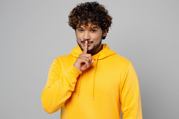 Young secret fun Indian man 20s he wear casual yellow hoody say hush be quiet with finger on lips...