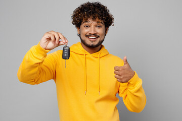 Young happy fun cool cheerful Indian man 20s he wearing casual yellow hoody hold car keys fob...