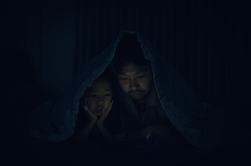 Dad and daughter sleep on the bed in bedroom,Watch cartoon with phone,Father day concept,Single dad,listen tale before sleep