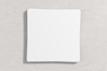Stack of square sheets of paper on the white wooden table.