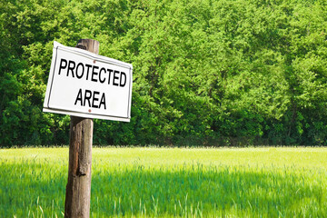 Protected area written on a sign against a woodland - Sign indicating concept