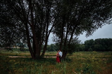 An elegant man in a shirt hugs a slender girl.