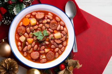 Asturian fabada with broad beans and Iberian chorizo ​​on a table decorated with Christmas motifs. Typical recipe from northern Spain.